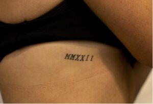 A tattoo in black Roman numerals spelling out "MMXXII" signifying the year “2022” is shown on Katie Thompson’s ribs.
