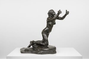 A dark bronze sculpture of a nude woman falling forward with outstretched arms sits in front of a white backdrop.
