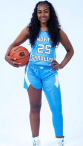 UNC guard Deja Kelly poses wearing her Carolina Blue jersey with a compression sleeve of the same color on her left leg.